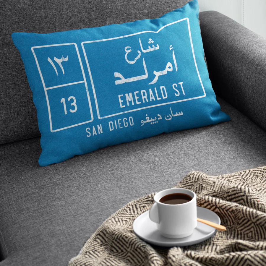 A customized pillow reading Emerald St, San Diego, on a gray sofa