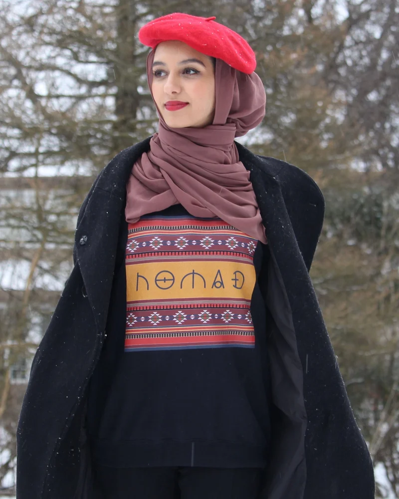 A woman in a red beret wearing the Nomad sweatshirt in the snow